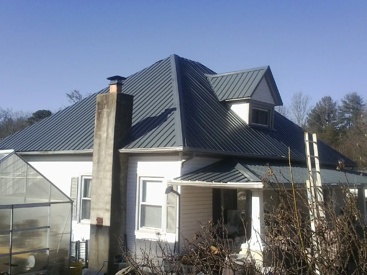 Dark blue standing seam metal roof on a white farmhouse with dormer — Slate & Tile Roof Repair by Roofing Brothers in Claypool