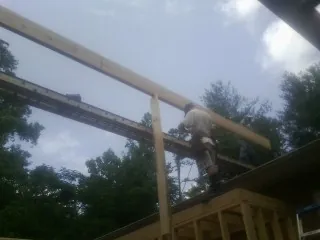 Carpenter setting a ridge beam over a new addition frame — Ice Dam Removal by Roofing Brothers in Claypool