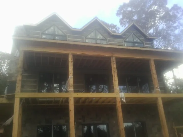 Dormers and porch framing on a large log home under construction — Roof Coating work by our crew in Claypool