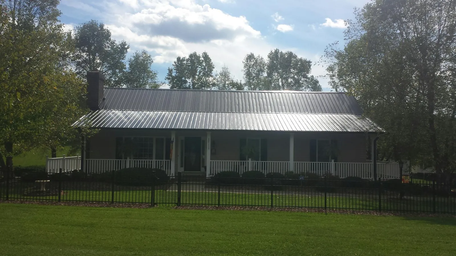 Gray metal roof on a brick ranch with a full width front porch — Gutter Guard Installation work by our crew in Claypool