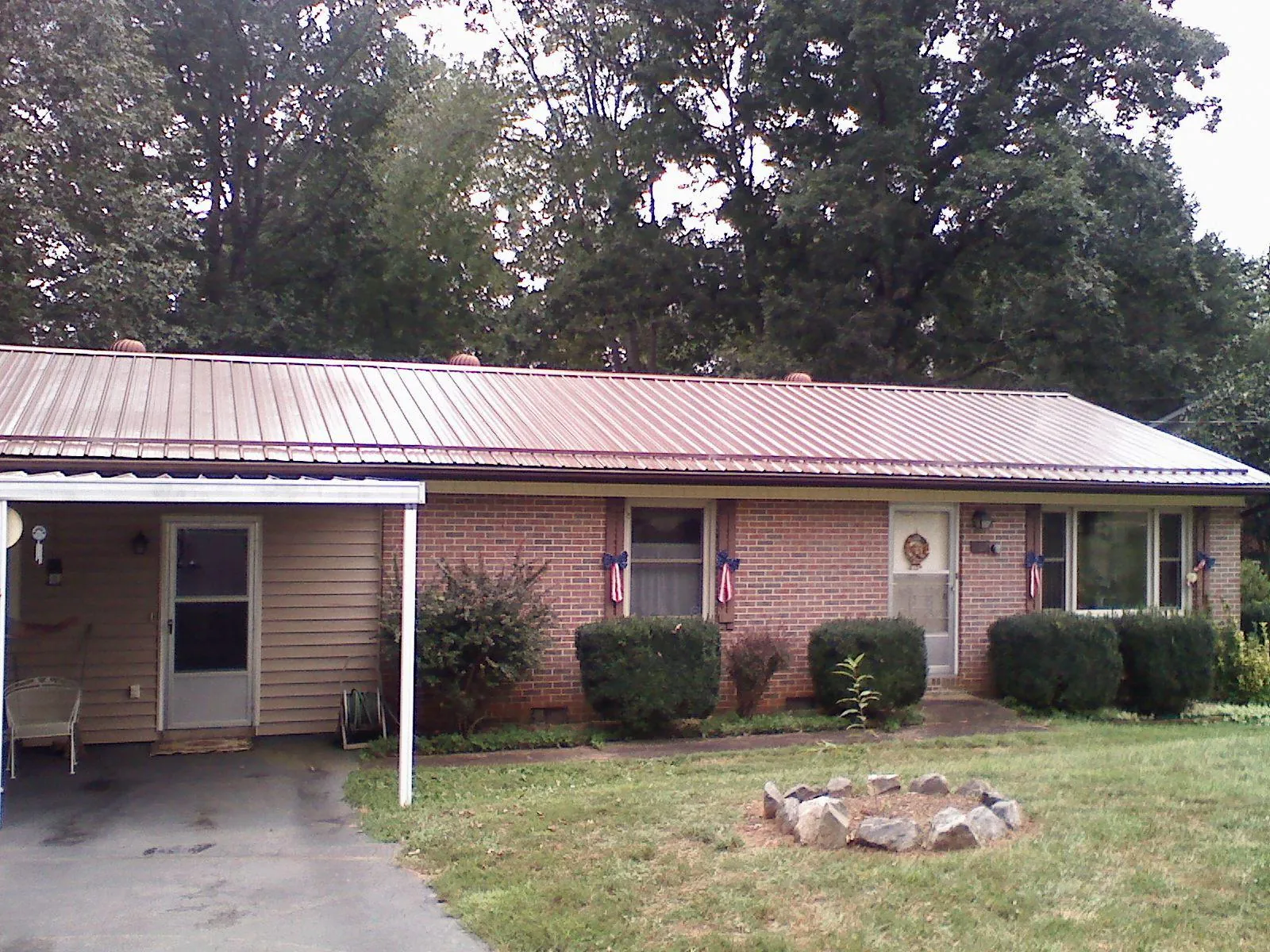 Bronze metal roof and carport on a brick ranch home — Roof Repair work by our crew in Claypool