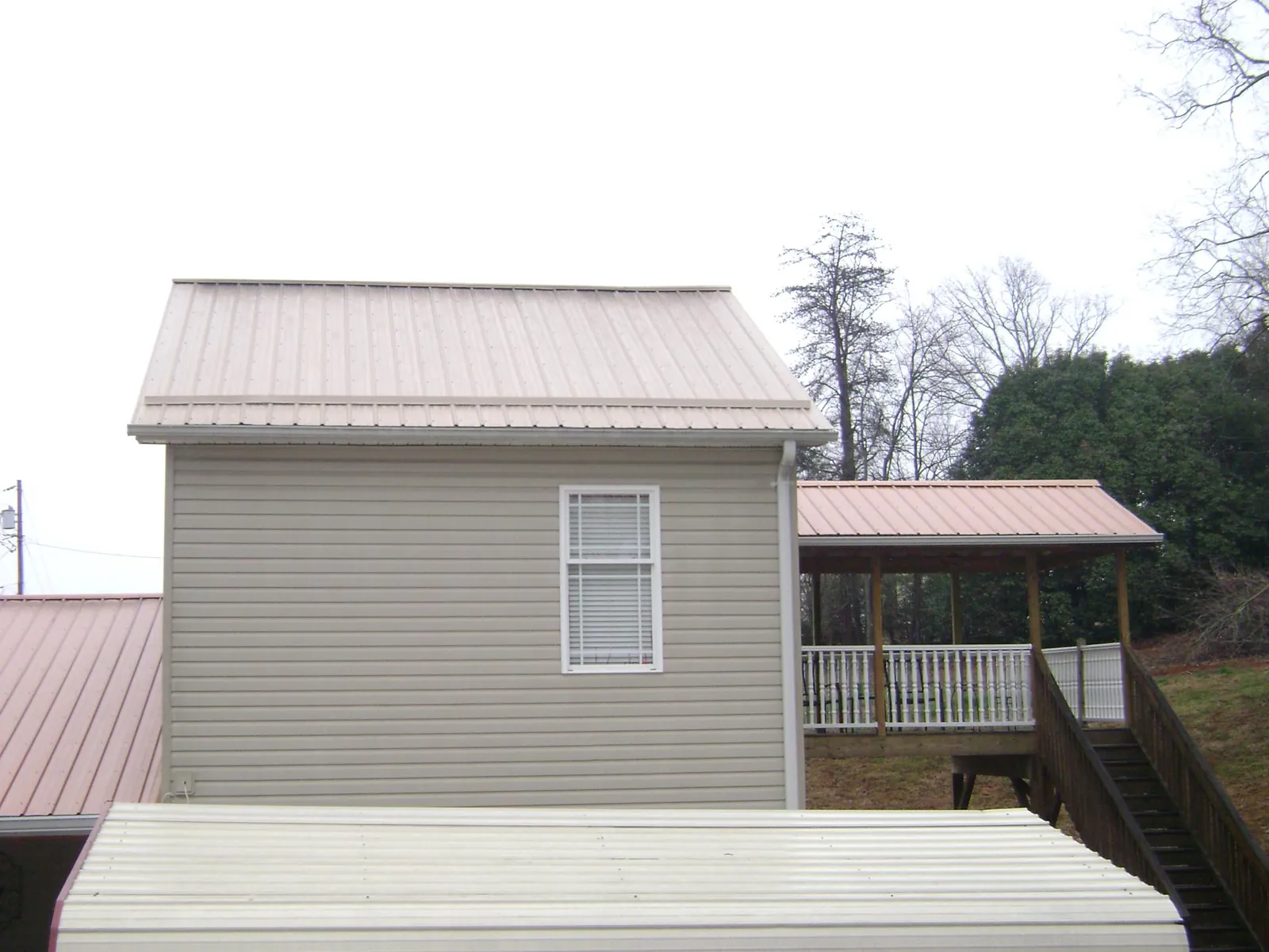 Tan metal roofs on a two story addition and attached porch, from a Roof Replacement job in Claypool