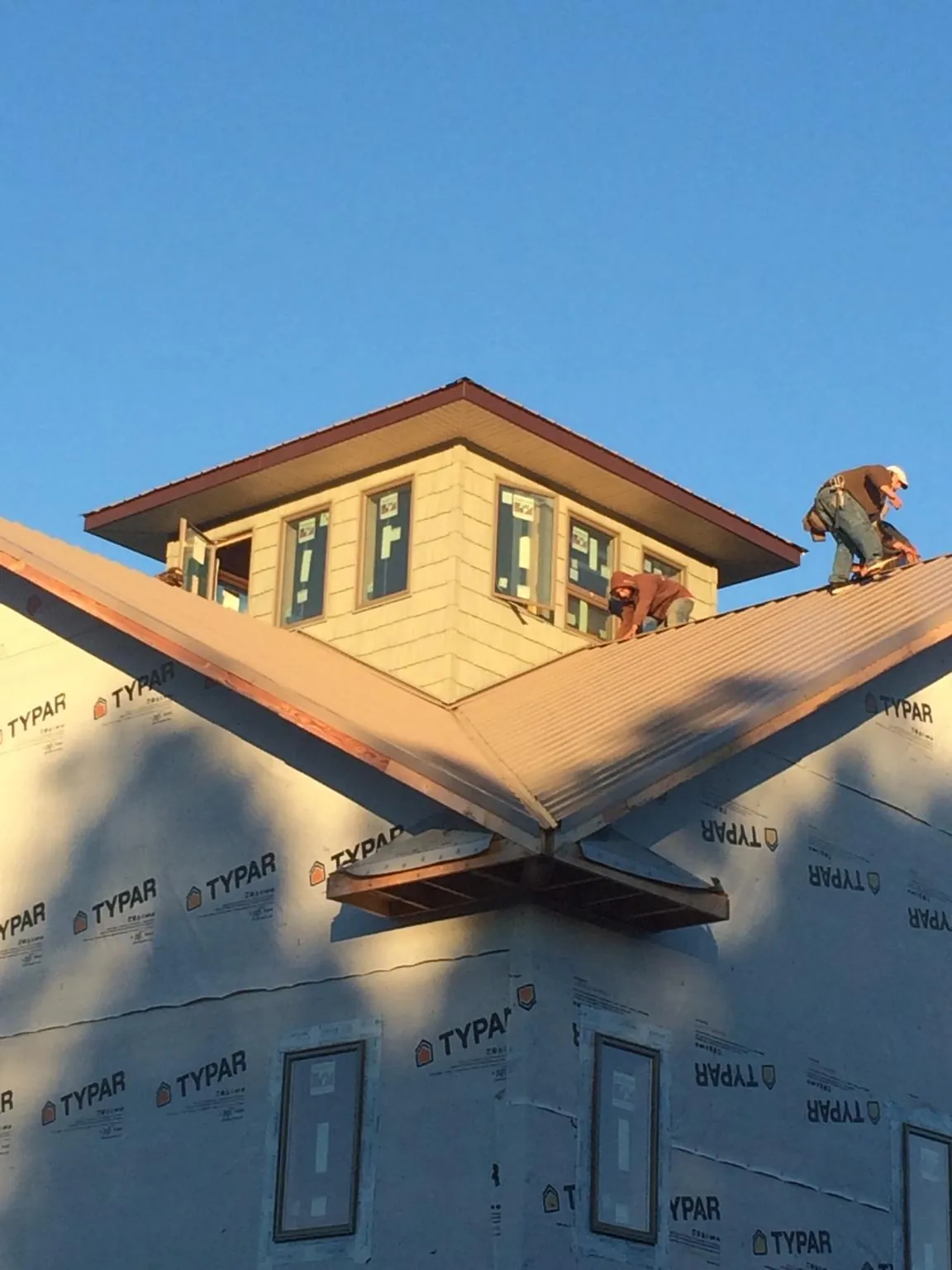 Roofers working around a rooftop cupola on a new metal roof at sunset — Roof Waterproofing in Claypool by Roofing Brothers